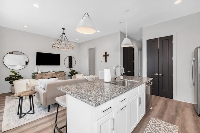 kitchen featuring a sink, white cabinets, a kitchen island with sink, appliances with stainless steel finishes, and wood finished floors