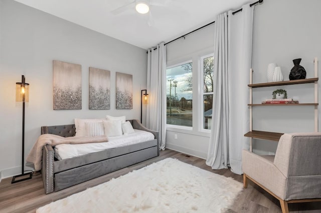 bedroom featuring baseboards, wood finished floors, and a ceiling fan