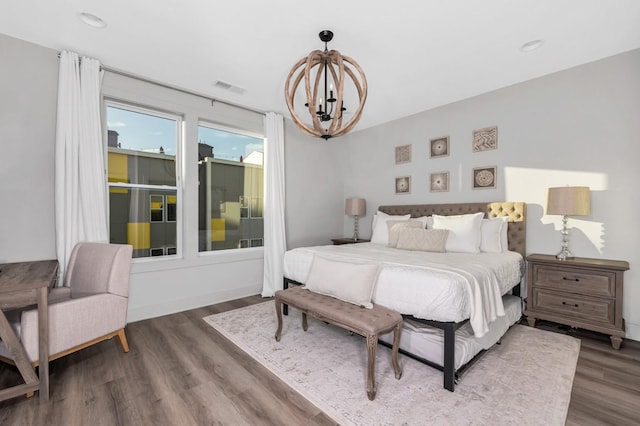 bedroom with visible vents, wood finished floors, and a chandelier