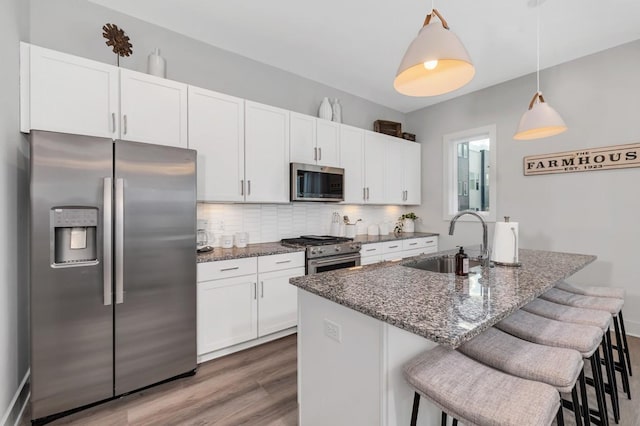kitchen featuring a sink, a breakfast bar area, white cabinets, and appliances with stainless steel finishes