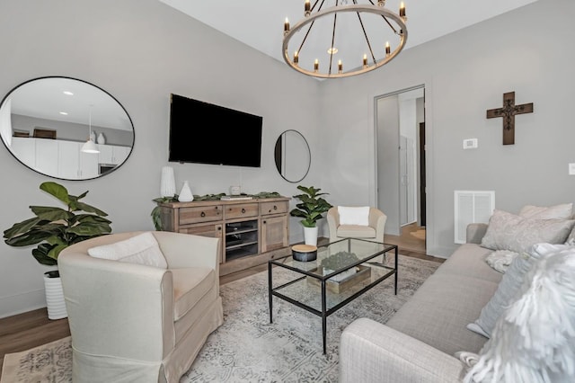living area with baseboards, visible vents, wood finished floors, and a chandelier