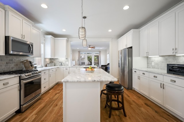 5311 Tennessee Ave Unit A, Nashville, TN 37209 - kitchen with white cabinets, stainless steel appliances, light wood-type flooring, a breakfast bar area, and a center island