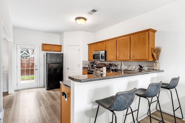 284 Meigs Dr Unit C21, Murfreesboro, TN 37128 - kitchen with brown cabinets, decorative backsplash, black appliances, and light wood finished floors