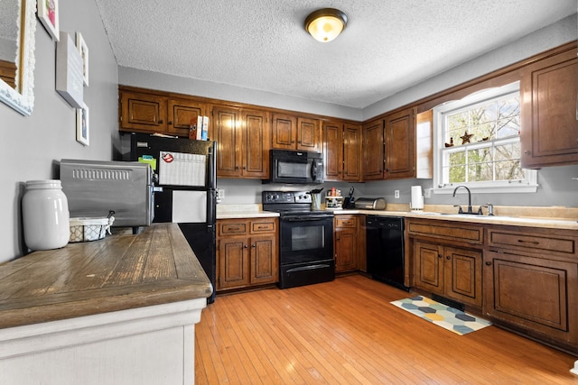 740 Acorn Dr, Clarksville, TN 37043 - kitchen with a sink, a textured ceiling, brown cabinets, light wood-style flooring, and black appliances