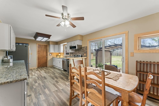 dining room featuring baseboards, light wood-style floors, and ceiling fan