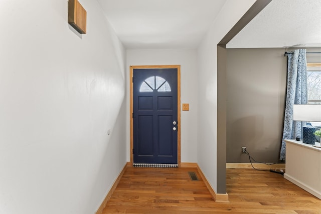 foyer entrance with baseboards, visible vents, and light wood-style flooring