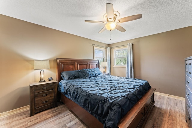 bedroom with baseboards, a textured ceiling, ceiling fan, and light wood-type flooring