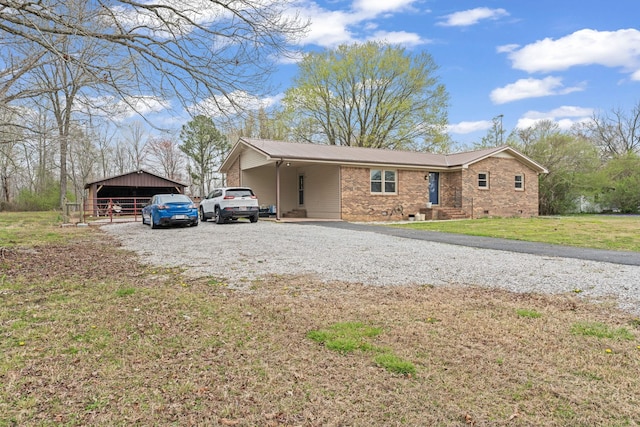 ranch-style home featuring a front lawn, driveway, an outbuilding, and metal roof