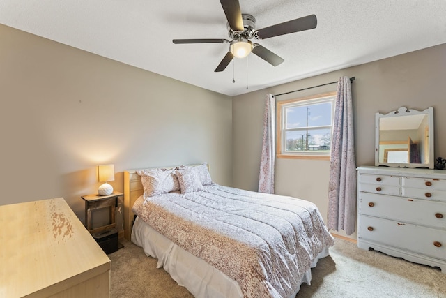 bedroom with light colored carpet, a ceiling fan, and a textured ceiling