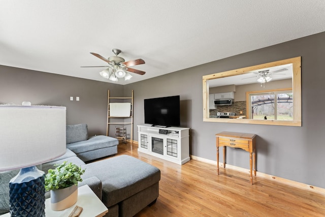 living room featuring baseboards, wood finished floors, and a ceiling fan