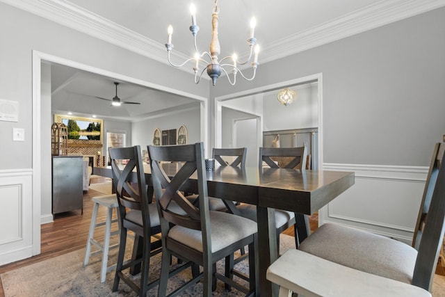 dining room featuring a decorative wall, a wainscoted wall, ornamental molding, and wood finished floors