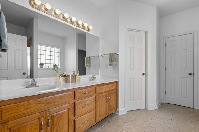 bathroom with baseboards, double vanity, a sink, and tile patterned floors