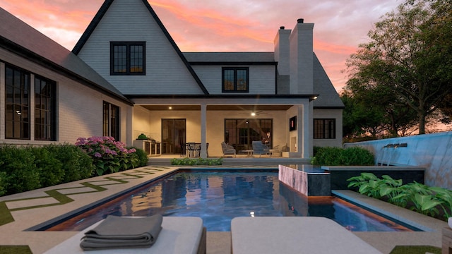 1352 Duncanwood Ct, Nashville, TN 37204 - back of house at dusk with a chimney, a patio area, and a fenced in pool