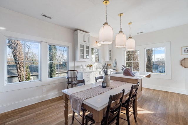 dining space featuring baseboards, visible vents, and light wood-style floors