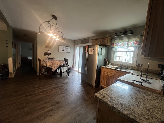kitchen with dark wood finished floors, brown cabinets, a sink, and freestanding refrigerator