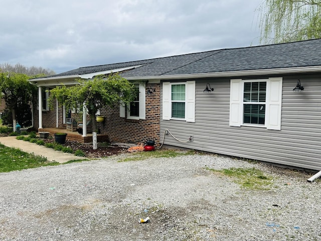 view of property exterior with a shingled roof and brick siding