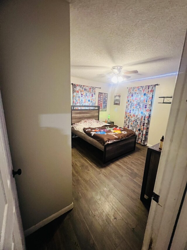 bedroom featuring baseboards, a textured ceiling, wood finished floors, and a ceiling fan