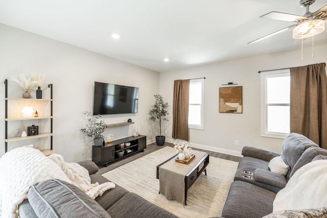 living area with baseboards, wood finished floors, ceiling fan, and a healthy amount of sunlight