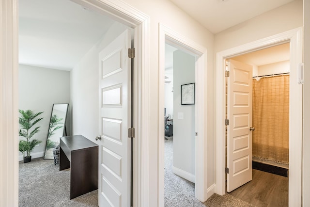 hallway featuring baseboards and carpet