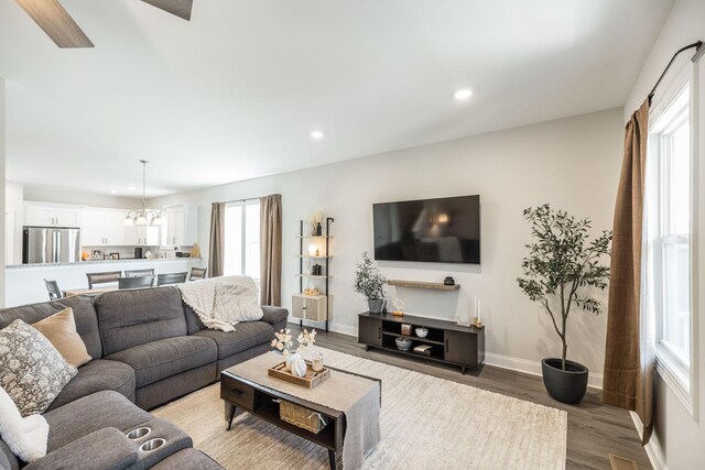 living area featuring baseboards, light wood-style floors, a chandelier, and recessed lighting