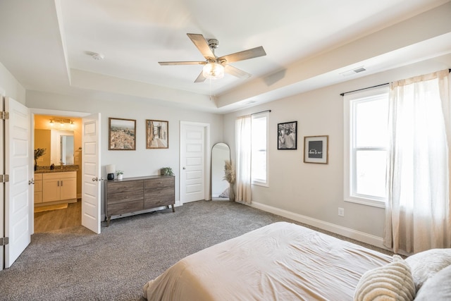 bedroom featuring carpet floors, a tray ceiling, baseboards, and ceiling fan