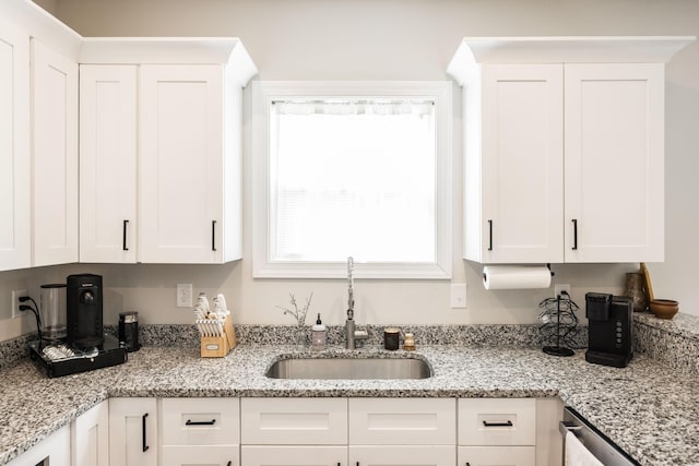 kitchen featuring white cabinets, light stone countertops, a sink, and dishwasher