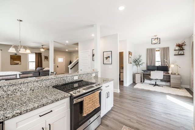kitchen with open floor plan, stainless steel range with electric cooktop, a wealth of natural light, and white cabinetry