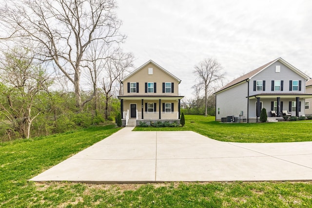 traditional-style house featuring a front lawn, covered porch, and central AC