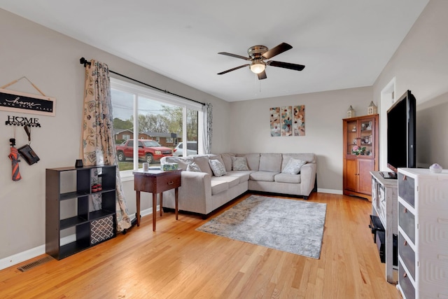 living area with a ceiling fan, visible vents, baseboards, and wood finished floors