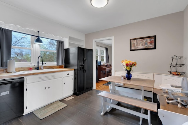 kitchen featuring white cabinetry, light countertops, a sink, and black appliances