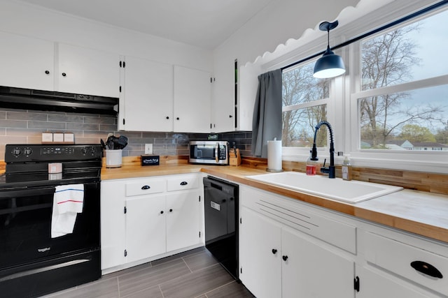 kitchen with light countertops, under cabinet range hood, a sink, and black appliances