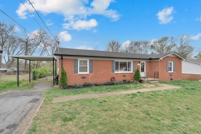 ranch-style house with fence, driveway, a front yard, brick siding, and a carport