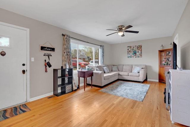 living area featuring baseboards, ceiling fan, and light wood-type flooring
