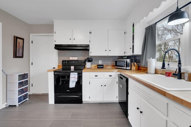 kitchen featuring light countertops, under cabinet range hood, white cabinetry, a sink, and black appliances
