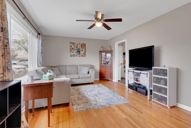 living area featuring baseboards, wood finished floors, and a ceiling fan