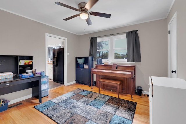 interior space featuring ornamental molding, baseboards, visible vents, a ceiling fan, and wood finished floors