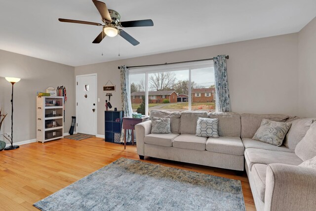 living room featuring baseboards, ceiling fan, and light wood-type flooring