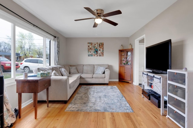 living area with baseboards, wood finished floors, and a ceiling fan
