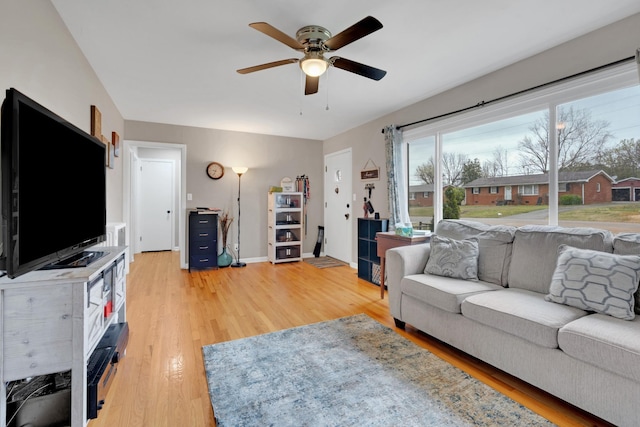 living area with baseboards, light wood-style flooring, and ceiling fan