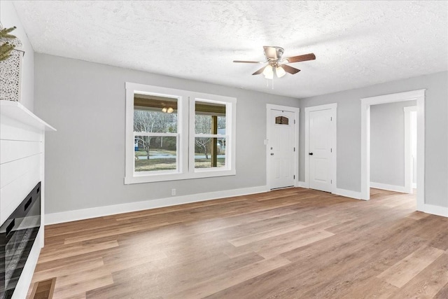 unfurnished living room with light wood finished floors, visible vents, a fireplace, and a ceiling fan