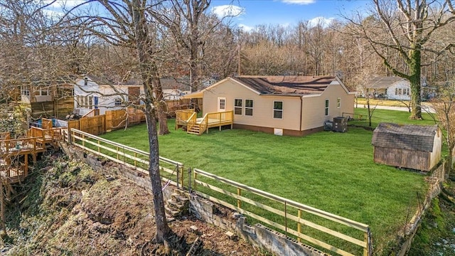 back of property featuring a shed, a wooden deck, an outbuilding, and a yard