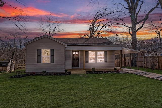 view of front facade with fence, a yard, and a carport