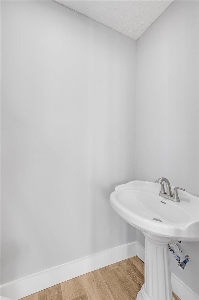 bathroom with baseboards, wood finished floors, and a textured ceiling