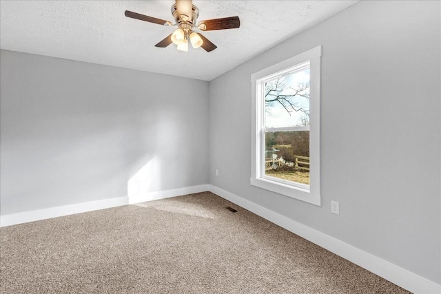 carpeted empty room featuring baseboards, visible vents, ceiling fan, and a textured ceiling