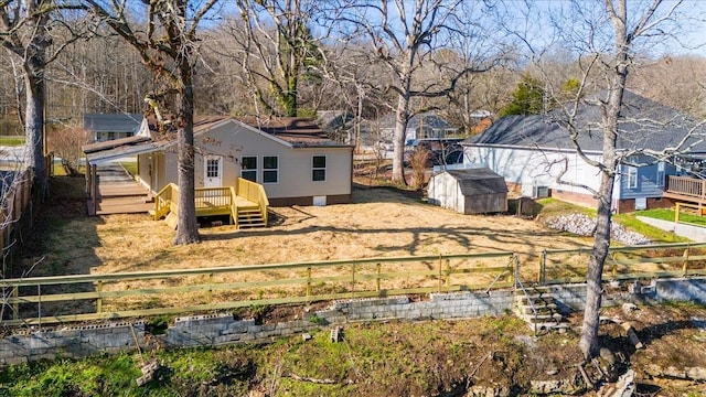 view of yard featuring a storage unit, a fenced backyard, a deck, and an outbuilding