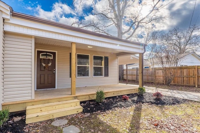 property entrance featuring covered porch and fence