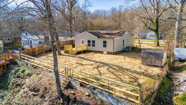 back of property featuring a fenced backyard, an outdoor structure, a storage shed, and a deck