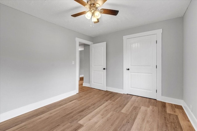 unfurnished bedroom with baseboards, light wood-type flooring, and a textured ceiling