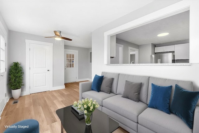 living area featuring baseboards, ceiling fan, visible vents, and light wood-type flooring