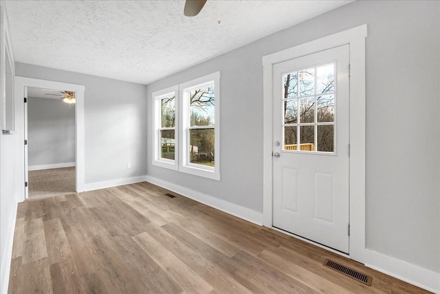 foyer featuring visible vents, a textured ceiling, wood finished floors, and a ceiling fan